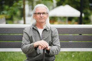 Old gray-haired man rest on the bench in summer park photo