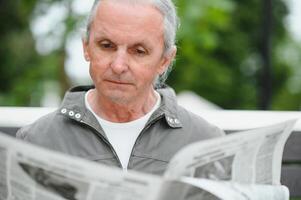 Old gray-haired man rest on the bench in summer park photo