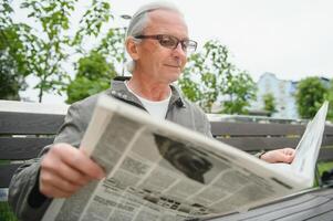 Old gray-haired man rest on the bench in summer park photo