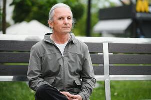 Old gray-haired man rest on the bench in summer park photo