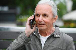 Old man browsing app on smartphone, outdoor in park photo