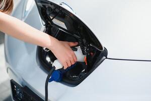 eco eléctrico coche concepto. mujer esperando eléctrico coche a cargar. foto