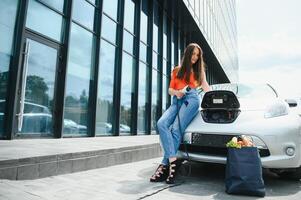 Eco electric car concept. Woman waiting electric car to charge. photo