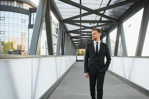 Stockbroker near the office. A successful and advanced handsome business man in a suit looks up in front of him standing on the background of concrete steps. photo