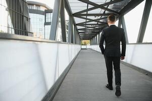 corredor de valores cerca el oficina. un exitoso y avanzado hermoso negocio hombre en un traje mira arriba en frente de él en pie en el antecedentes de hormigón pasos. foto