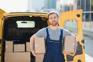 delivery service employee. Portrait of man working in delivery service. Portrait of courier with box. Courier next to minivan. Delivery service career. photo