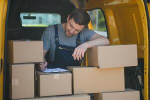 My deliveries are all running on schedule. Portrait of a delivery man unloading boxes from his van. photo