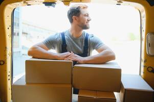 My deliveries are all running on schedule. Portrait of a delivery man unloading boxes from his van. photo