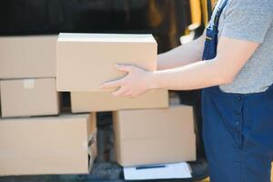 delivery service employee. Portrait of man working in delivery service. Portrait of courier with box. Courier next to minivan. Delivery service career. photo