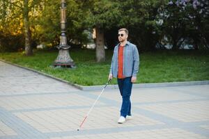 Blind Man Walking On Sidewalk Holding Stick photo