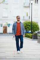 Blind Man Walking On Sidewalk Holding Stick photo