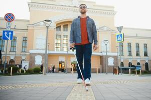 Handsome blind man walks around the city. photo