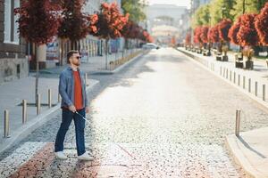 Blind young man crossing road photo