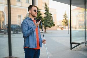 Young blinded man using phone and sending voice message photo