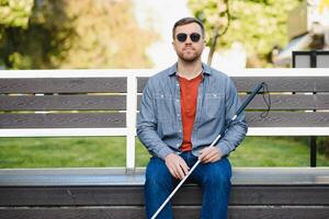 Blind man. People with disability, handicapped person and everyday life. Visually impaired man with walking stick. photo