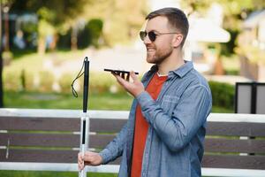 Young blinded man using phone and sending voice message photo