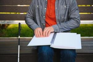 Blind man reading book on bench in park photo