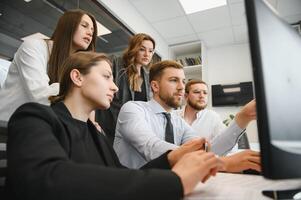 Smiling business people sitting at a desk in front of a laptop computer photo