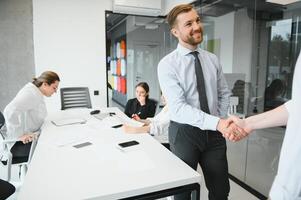 sonriente masculino negocio socios negociadores apretón de manos comienzo grupo oficina negociación, empresa representantes acogedor sacudir manos a reunión consiguiendo familiarizado expresando el respeto hacer financiero acuerdo foto