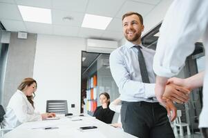 sonriente masculino negocio socios negociadores apretón de manos comienzo grupo oficina negociación, empresa representantes acogedor sacudir manos a reunión consiguiendo familiarizado expresando el respeto hacer financiero acuerdo foto