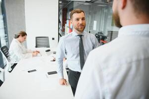 sonriente masculino negocio socios negociadores apretón de manos comienzo grupo oficina negociación, empresa representantes acogedor sacudir manos a reunión consiguiendo familiarizado expresando el respeto hacer financiero acuerdo foto