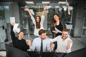 sonriente negocio personas sentado a un escritorio en frente de un ordenador portátil computadora foto