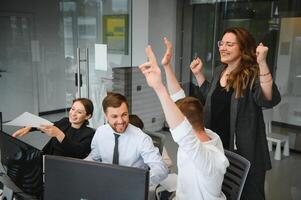 Smiling business people sitting at a desk in front of a laptop computer photo