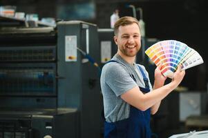 Portrait of worker at control room checking print quality at printing house. photo