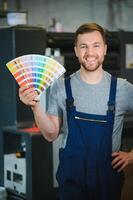 Portrait of worker at control room checking print quality at printing house. photo