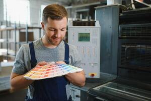 Man working in printing house with paper and paints photo