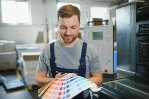 Man working in printing house with paper and paints photo