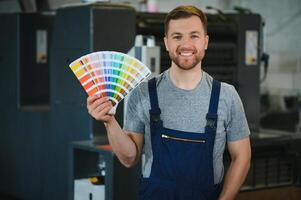 Man working in printing house with paper and paints photo