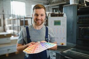 Man working in printing house with paper and paints photo