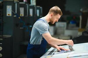 Portrait of worker at control room checking print quality at printing house. photo