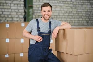 Portrait of happy male worker in warehouse standing between shelves. photo