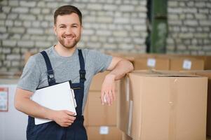 Portrait of happy male worker in warehouse standing between shelves. photo