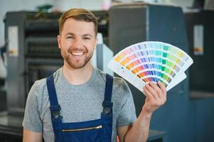 Man working in printing house with paper and paints photo