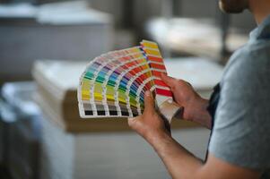 Man working in printing house with paper and paints photo