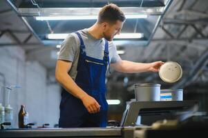 Portrait of production line worker controlling manufacturing process of modern packaging industrial machine in printing factory photo