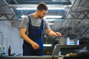 Portrait of production line worker controlling manufacturing process of modern packaging industrial machine in printing factory photo