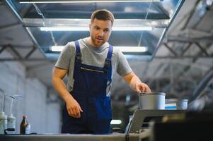 Man working in printing house with paper and paints photo