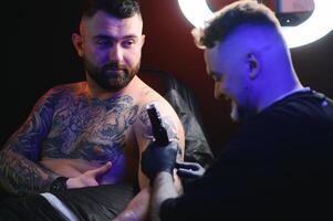 tatuaje artista manos vistiendo guantes y participación un tatuaje máquina foto