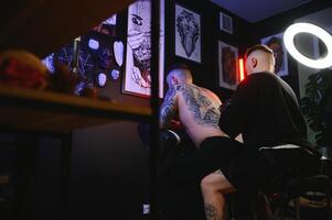 tatuaje artista hombre con negro guantes sorteos un Caballero tatuaje en el tipo espalda en el estudio. tatuaje del artista flujo de trabajo foto