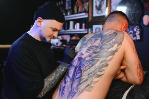 Disparo de un tatuaje artista manos formando Perfecto líneas en hombre espalda con tinta foto