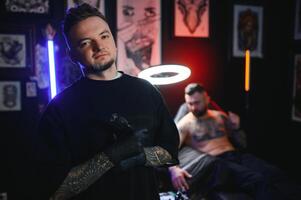 tattoo artist demonstrates the process of getting black tattoo with paint. Master works in black sterile gloves photo