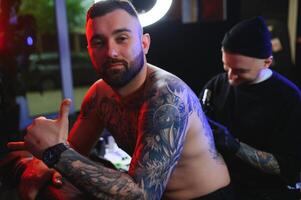 tatuando hombre creando un imagen en su espalda por un profesional tatuaje artista foto