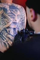 tatuaje artista hombre con negro guantes sorteos un Caballero tatuaje en el tipo espalda en el estudio. tatuaje del artista flujo de trabajo foto