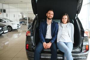 es el único coche que quiero. Hermosa joven pareja de pie en el concesionario eligiendo el coche para comprar foto