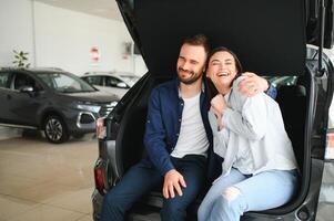 es el único coche que quiero. Hermosa joven pareja de pie en el concesionario eligiendo el coche para comprar foto