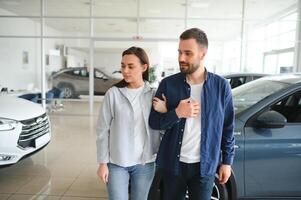 The successful visit to the dealership. Happy young couple chooses and buying a new car for the family photo